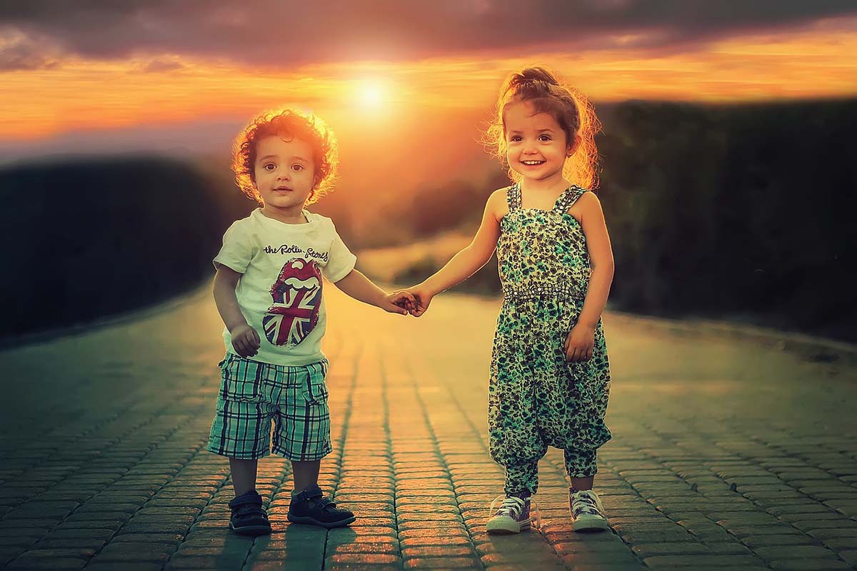 children holding hands and behind them a sunset